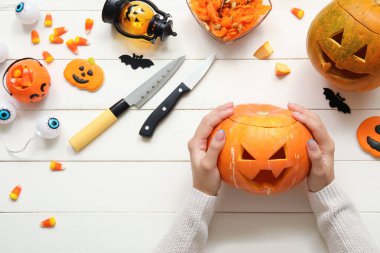 Beyaz ahşap masada oyulmuş Cadılar Bayramı kabağı olan kadın.