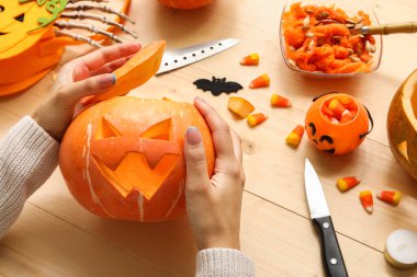 Ahşap masada oyulmuş Cadılar Bayramı kabağı olan kadın.