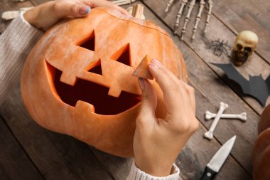 Ahşap masada oyulmuş Cadılar Bayramı kabağı olan kadın.