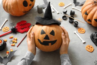 Gri grunge masasında boyalı Cadılar Bayramı kabağı olan kadın.