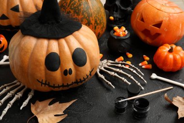 Siyah grunge masasında Cadılar Bayramı süsleriyle boyanmış balkabağı.