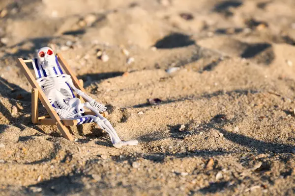 Cadılar Bayramı için iskelet ve kumsalda iskele sandalyesi.