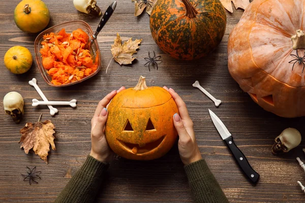 Ahşap masada oyulmuş Cadılar Bayramı kabağı olan kadın.