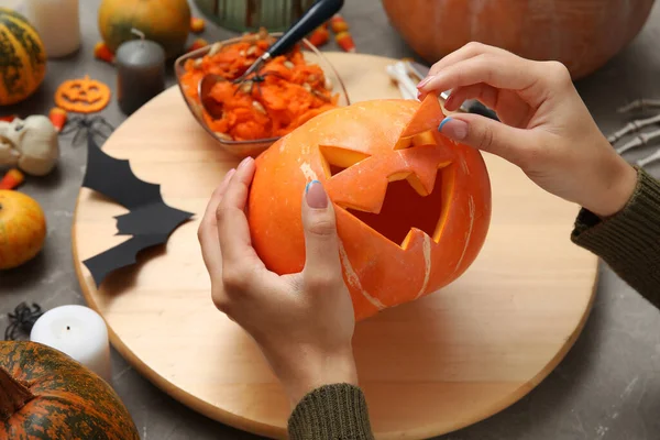 Gri grunge masasında oyulmuş Cadılar Bayramı kabağı olan kadın.