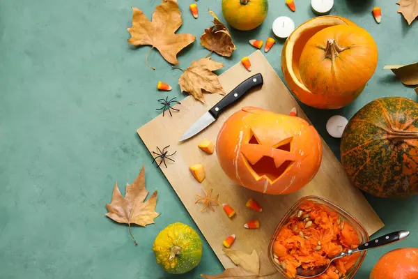 Yeşil grunge masasına oyulmuş balkabağı, bıçak ve Cadılar Bayramı süslemeleri.