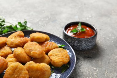 Lezzetli nugget tabağı, bir kase ketçap ve gri grunge masasında otlar.