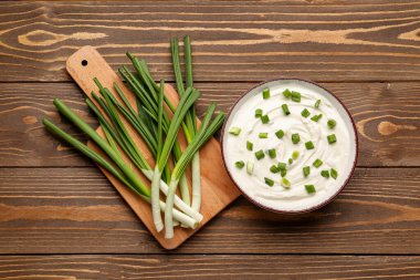 Ahşap arka planda yeşil soğanlı bir kase lezzetli ekşi krema.