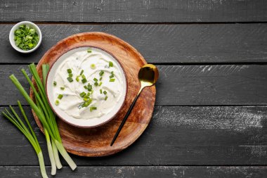 Koyu ahşap arka planda yeşil soğanlı bir kase lezzetli ekşi krema