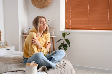 Yatak odasında kaşınan alerjisi olan genç bir kadın.