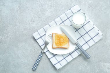 Şeftali reçeli, süt ve çatal bıçaklı lezzetli tost tabağı grunge grisi arka planda.