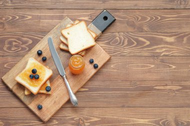 Şeftali reçelli lezzetli tost tahtası ve kahverengi ahşap arka planda yabanmersini.