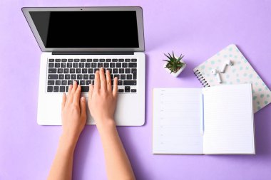 Kulaklık ve mor arkaplan üzerine not defteri kullanan kadın programcı