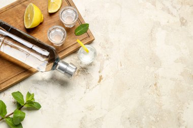 Hafif arka planda limonlu bir şişe ve bir bardak votka.