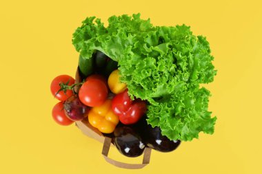 Sarı arka planda taze sebzeli kağıt torba. Sağlıklı gıda konsepti