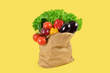 Sarı arka planda taze sebzeli kağıt torba. Sağlıklı gıda konsepti