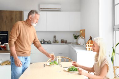 Olgun bir çift mutfakta yemek yiyor.