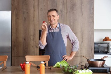 Mutfakta taze domatesli olgun bir adam.