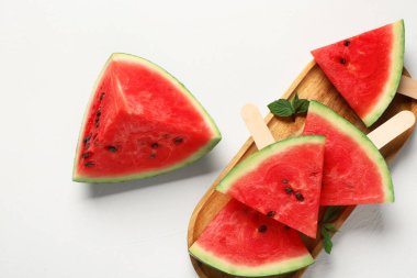 Tahta tahta, tatlı karpuz çubukları ve beyaz arka planda nane şekeri.