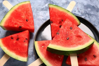 Mavi arka planda tatlı karpuz çubukları olan bir tabak.