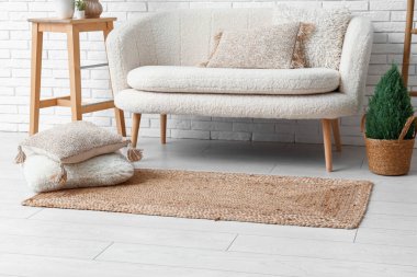 Interior of light living room with white sofa and wicker carpet
