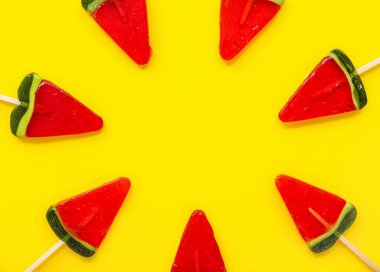 Sarı arka planda karpuz dilimi şeklinde lolipoplardan yapılmış çerçeve
