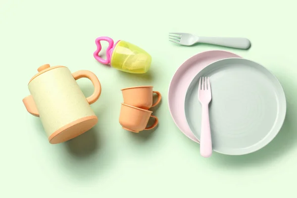 Different eating utensils for baby on pale green background
