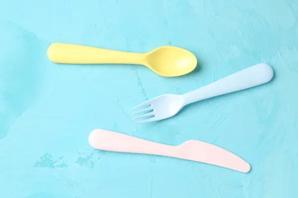 Colorful plastic cutlery for baby on grunge blue background