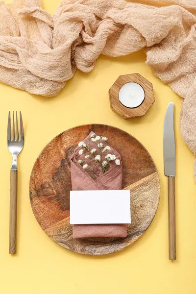 Yeşil çiçekli güzel bir masa, boş davetiye kartı ve sarı masadaki mum.