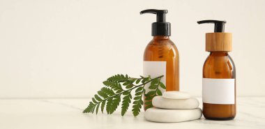 Beyaz arkaplanda doğal şampuan ve spa taşları ve metin için yer var.
