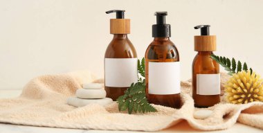 Beyaz arka planda doğal kozmetik şişeleri, fırça, havlu ve spa taşları