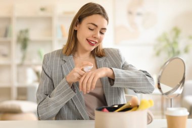 Makyaj vakfını evinde eline süren genç bir kadın.