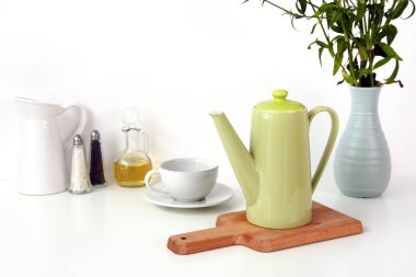 Çaydanlık, fincan ve beyaz masada farklı öğeler ile kompozisyon