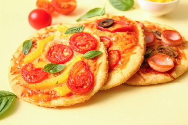 Sarı arka planda farklı lezzetli mini pizzalar.