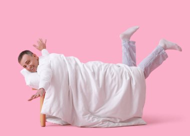 Yumuşak yastıklı ve pembe arka planda uzanan olgun bir adam.