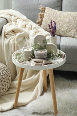 Oturma odasının içinde kanepe, çigila çiçekleri ve mumlar var.