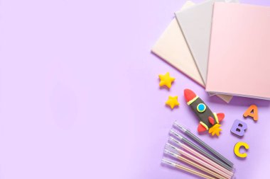 Eflatun arka planda farklı kırtasiye malzemeleriyle plastikten yapılmış roket