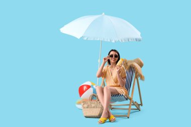 Mavi arka planda güneş kremi sürmüş genç bir kadın.