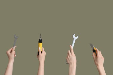 Electrician hands with tools on green background