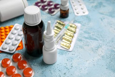 Farklı haplar, şırınga ve mavi arka planda ilaç şişeleri.