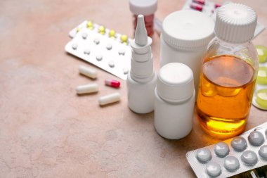 Pembe arka planda farklı haplar ve ilaç şişeleri