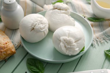 Yeşil ahşap arka planda fesleğenli lezzetli Burrata peyniri tabağı