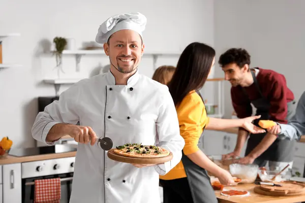 Italian chef with prepared pizza during cooking class in kitchen