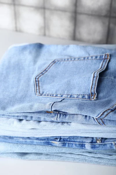Pila Jeans Sul Tavolo Vicino Parete Piastrelle Grigie — Foto Stock
