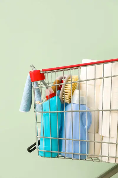 Açık Yeşil Arka Planda Temizlik Malzemeleriyle Dolu Bir Alışveriş Arabası — Stok fotoğraf