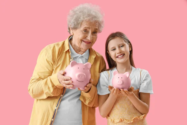 Menina Sua Avó Com Bancos Porquinhos Fundo Rosa — Fotografia de Stock
