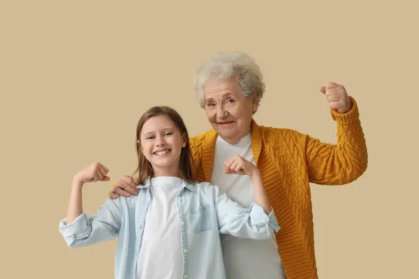 Menina Com Sua Avó Mostrando Músculos Fundo Bege — Fotografia de Stock
