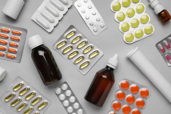 Different pills and bottles of medicines on grey background