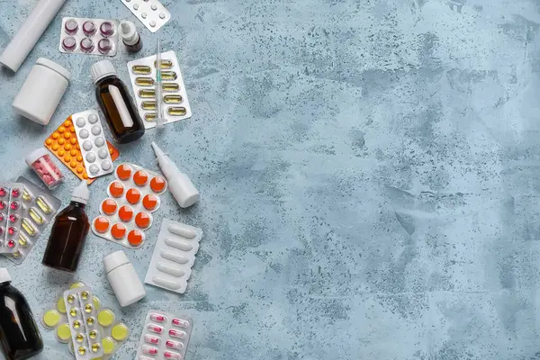 Different pills, syringe and bottles of medicines on blue background