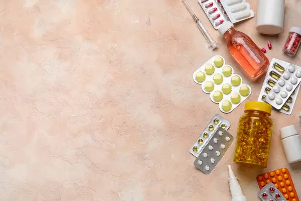Different pills, syringe and bottles of medicines on pink background