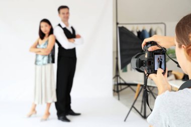Stüdyoda genç bir çiftin fotoğrafını çeken kadın fotoğrafçı.